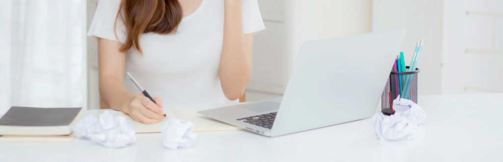 Young women working at a desk with a laptop and notebook.